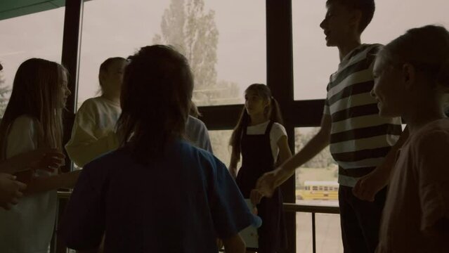 Group school bullies pushing outcast boy in hall. Children punching teen child.
