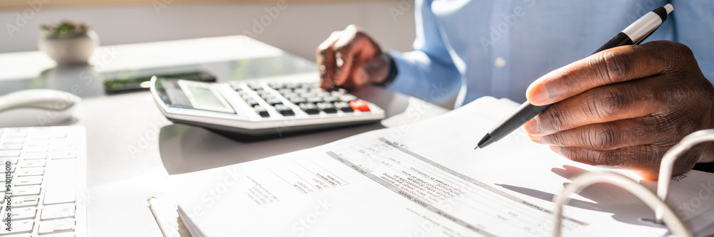 Poster smiling businessman calculating invoice on computer