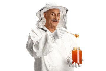 Bee keeper taking dipping a wooden dipper in a jar with honey
