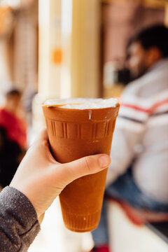 Woman holds traditional Indian lassi in a clay mug