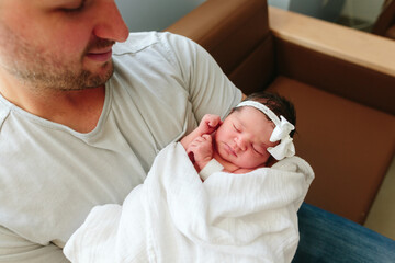 dad proudly holds newborn baby and smiles