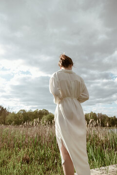 a girl is standing in a field in a light dress