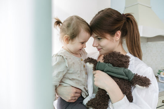portrait of mother and daughter, whose faces are next to each other, in a bright apartment