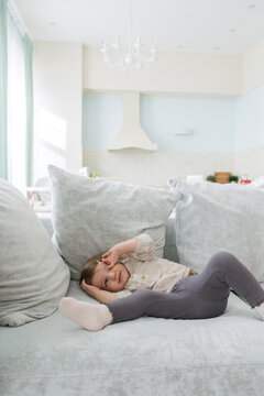 portrait of a little girl on a large bright sofa that lies on it and fools around