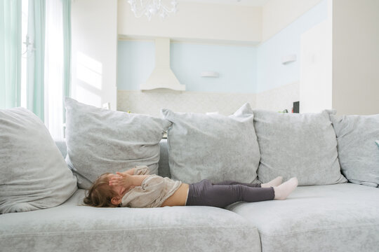 little girl lies on a large bright sofa in a spacious apartment