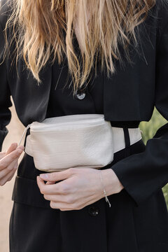 stylish black jacket and white belt bag on the girl while walking in the field