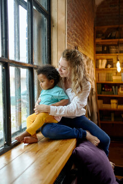 mom and little daughter look out the window