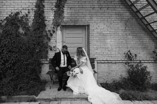 black and white photo of newlyweds sitting on a bench together wedding field