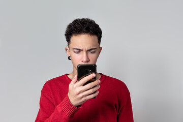 Young man looking at smartphone and expressing outrage