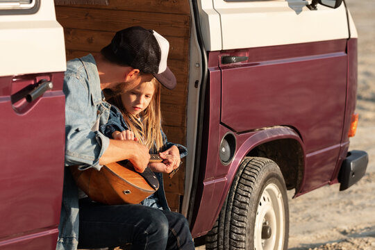 Child learning to play domra with dad in van