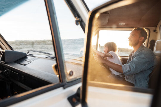 Dad and child driving van at sunrise