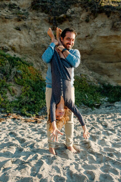 Dad holding daughter upside down by legs