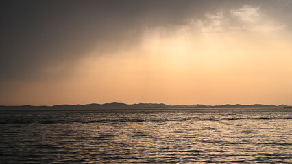 Stormy weather at the sea, view from a boat. Waves on the sea with dramatic clouds above at sunset. Rainy summer day. 