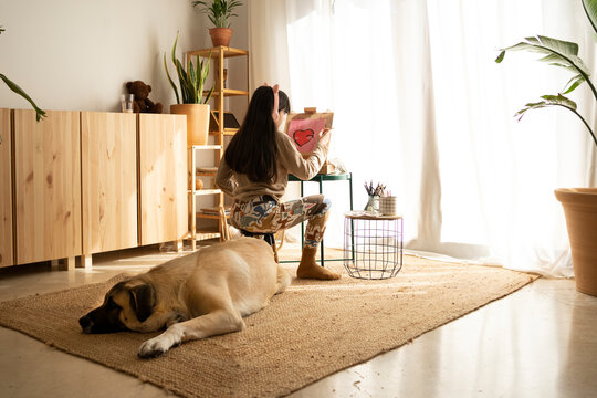 Girl with her dog drawing heart in living room