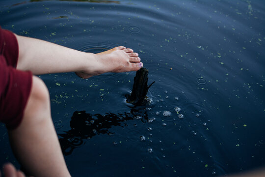 Childs feet against dark pond water