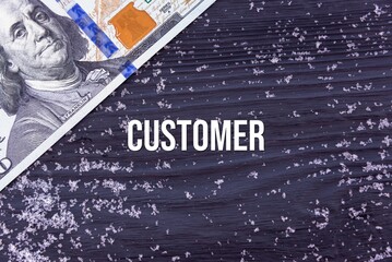CUSTOMER - word (text) on a dark wooden background, money, dollars and snow. Business concept (copy space).