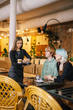 Waitress catering customers with ordered drinks 