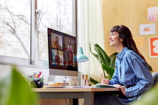 Positive Woman Making Notes During Virtual Meeting