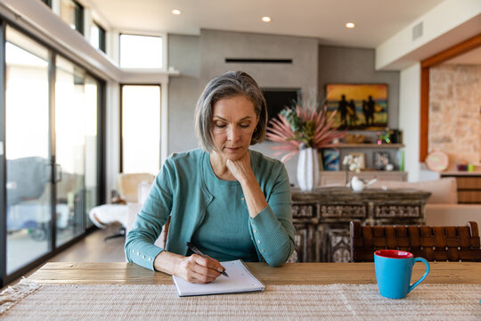 Focused Woman Writes In Her Notebook
