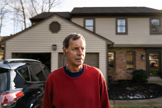 Retirement age man outside home with car