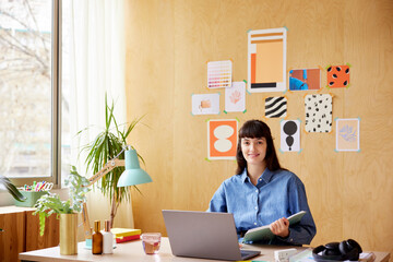 Smiling brunette working with notepad and laptop