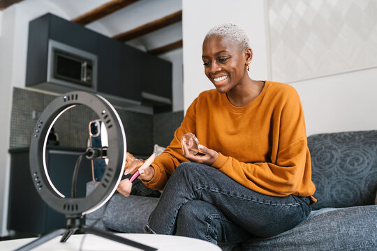 Happy beauty blogger recording video in living room