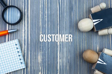 CUSTOMER - word (text) on a wooden background, notepad and pen with calculator. Business concept (copy space).
