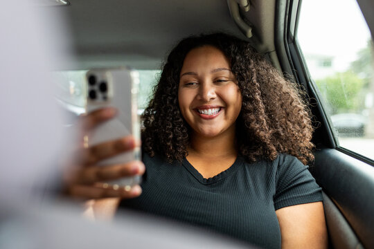 Woman Riding In Car Smiles At Smartphone 