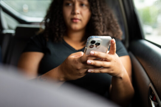 Young Woman Looks Hesitantly Ahead While Holding Her Smartphone 