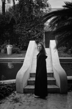 A woman in black coat by a pool