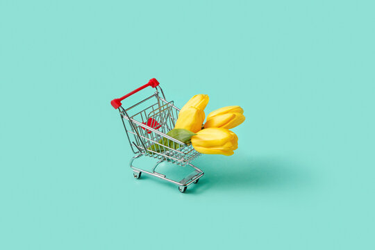 Small shopping trolley with bouquet of yellow tulips