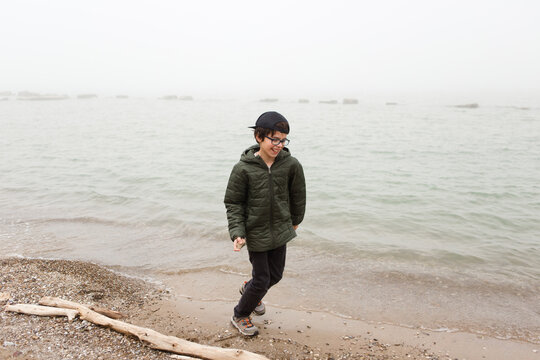 boy on foggy beach skipping stones