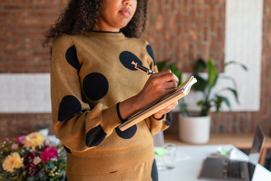 Cropped woman taking notes standing in office