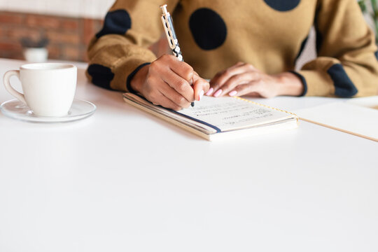 Cropped woman taking notes at desk