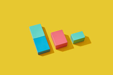 Colored wooden toy cubes lying on yellow background