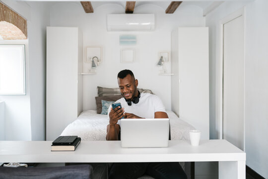 Happy black man using smartphone during remote work