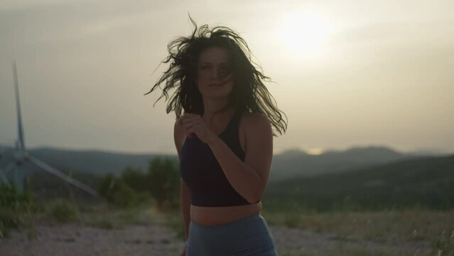 Close-up of a girl jogging in the mountains. The woman is actively involved in sports and runs against the sunset and mountain peaks.