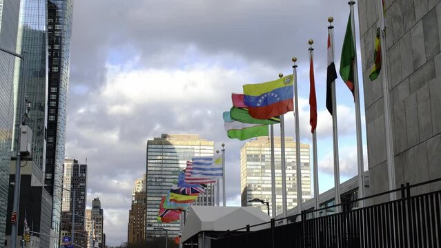 Venezuela, Vanuatu, Uruguay, flags on flag pole in front of UN in NYC. Flags flying in the wind. USA , tanzania flags