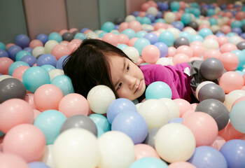 Adorable little Asian girl playing in the stack of bubble balls