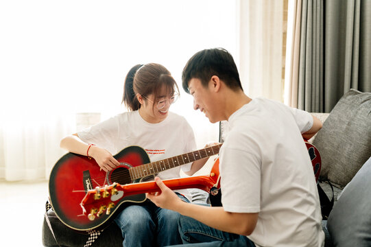 Young man teaching his friend how to play guitar