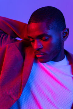 Portrait Of A Man Closing His Eyes Under Blue And Red Lights.