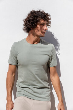 Dreamy young Hispanic man standing near white wall