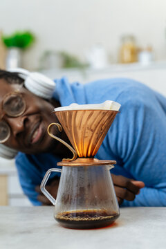 Young black man brewing filter coffee in a kitchen