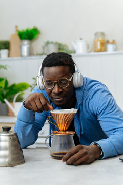 Young black man brewing filter coffee in a kitchen