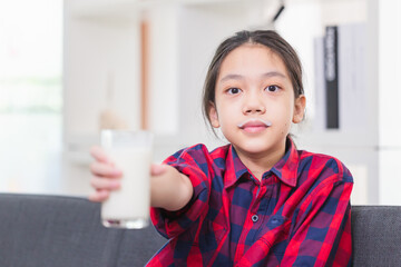 Happy child girl drinks milk, Portrait of Asian little cute kid holding a cup of milk in kitchen