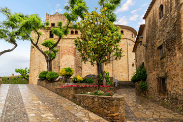 Fototapeta na wymiar The wet tree lined streets heading to the Església de Sant Pere cathedral at the medieval village of Pals, Spain after a summer rainstorm along the Costa Brava coast.