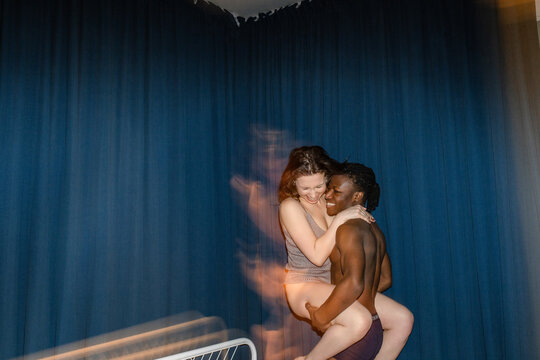 A half-naked guy holds his girlfriend in his arms and laughs