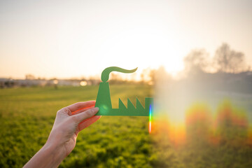 Hand holding green industry symbol in nature
