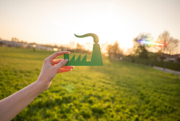 Hand holding green industry symbol in nature
