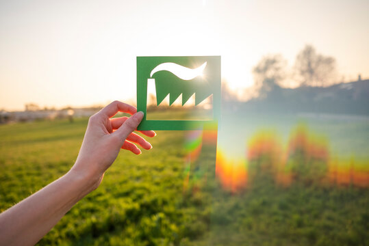 Hand holding green industry symbol in nature